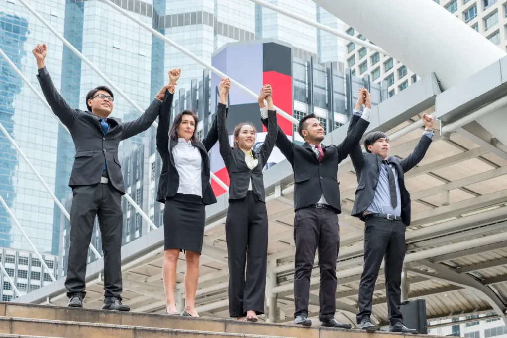 a group of businessmen raising hands for their success - a reason for acquisition